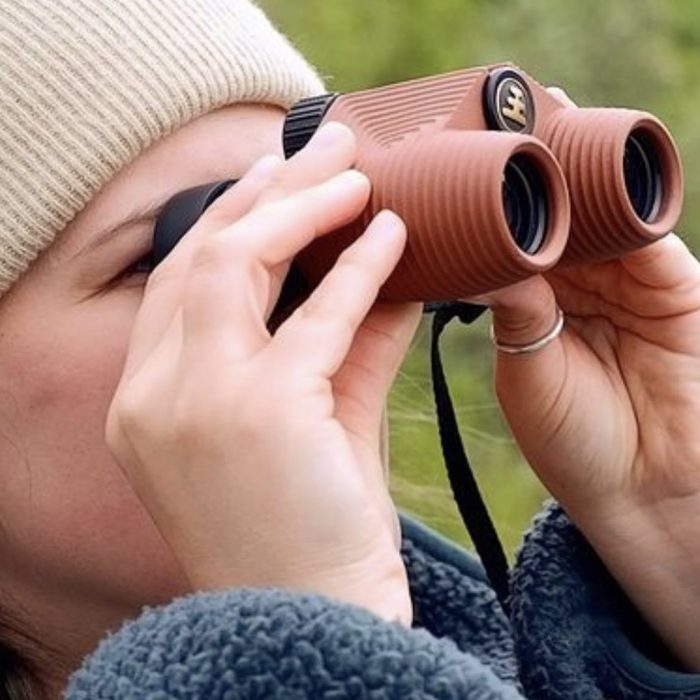 woman looking into nocs binoculars. image by field theory alaska