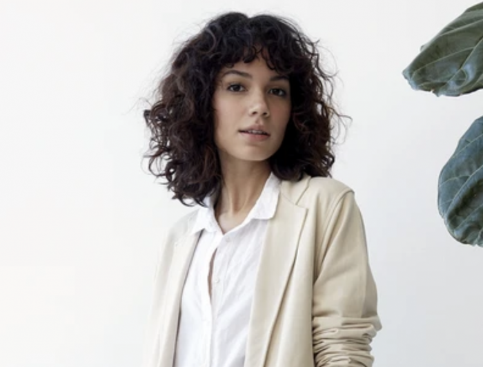 woman with curly hair standing with confidence in grey state blazer