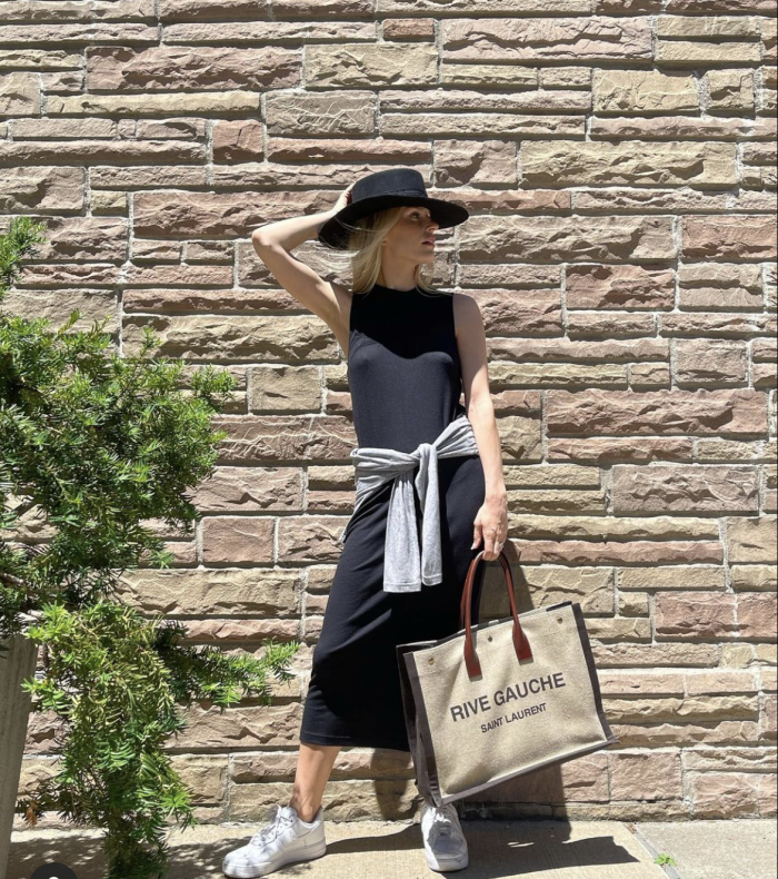 Woman posing in front of brick wall in naadam black maxi dress.