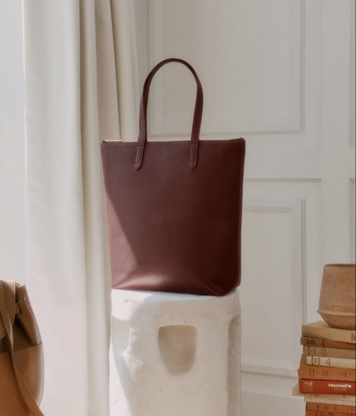 Leather tote sitting on white structure with natural light coming through window