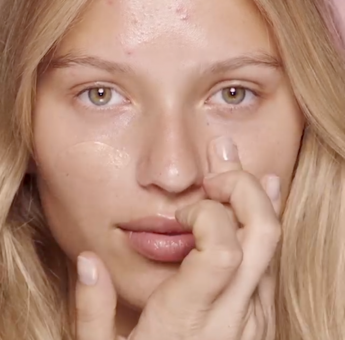 Woman putting face primer on white woman with blonde hair